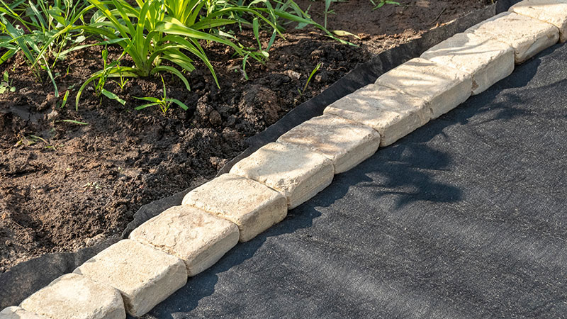 Weed Barrier with retaining wall blocks holding it down